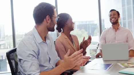 Businesspeople-interacting-and-applauding-a-coworker