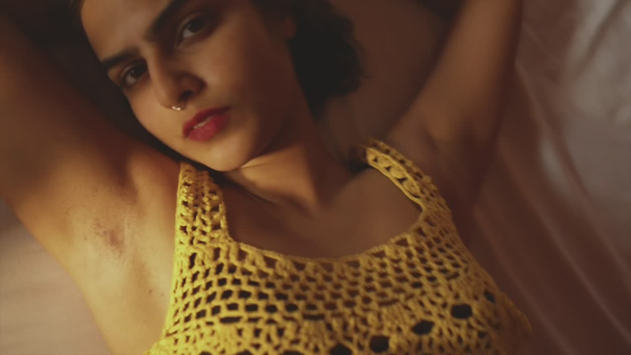 Beautiful Indian female model lying on a bed looking at the camera