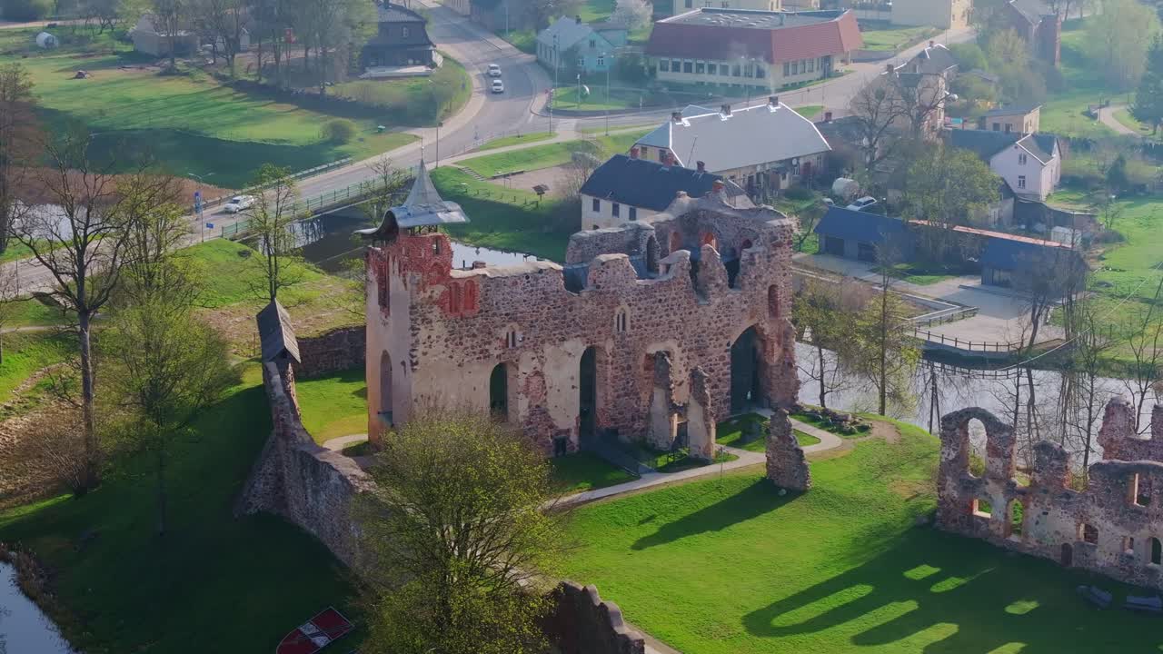 Ancient stone castle walls stand tall on hill in Dobele, surrounded by spring