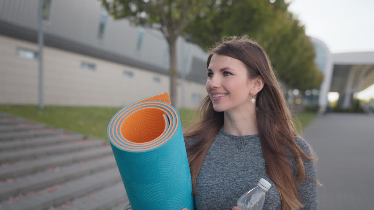 mujer con alfombra de yoga y botella de agua