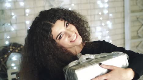 gift box new year day celebration. young attractive woman with gift box near fireplace