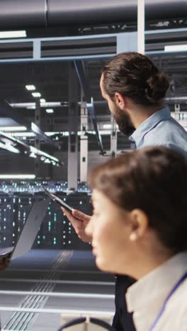 vertical video data scientists working together in server room, reviewing neural network code