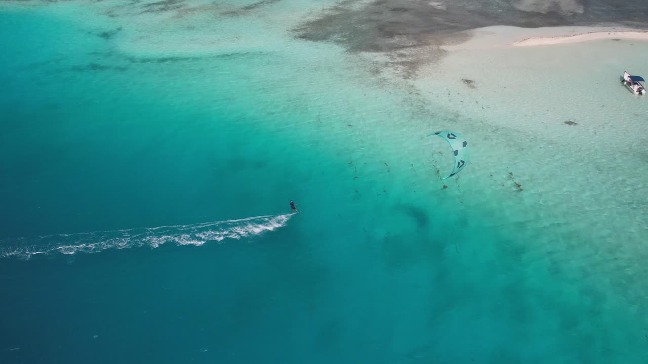 로스 로케스 의 모래 해변 근처 에 있는 푸른 물 위 를 날아다니는 카이트 서퍼