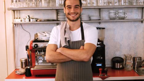 portrait of smiling waiter standing with arms crossed