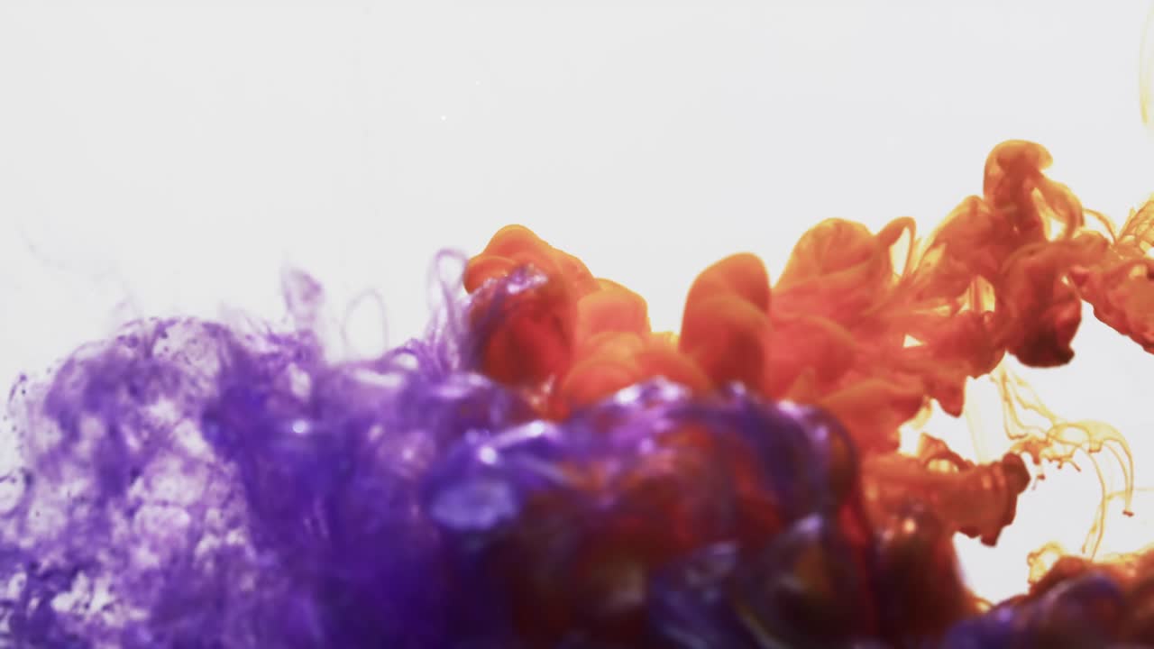 Slow motion video of purple and orange watercolor ink mixed in water against grey background