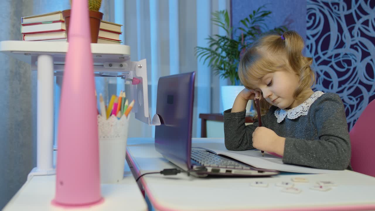 niño aburrido escuchando una lección de audio estudiando en la mesa usando una computadora portátil digital, haciendo la tarea