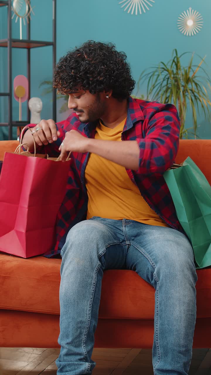 Happy indian man shopaholic consumer came back home after online shopping sale with bags at home