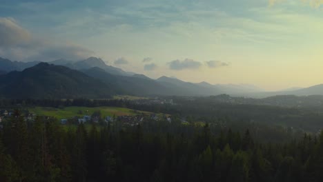 flying over forest near villages with chalet houses of cyrhla during sunrise in podhale region, southern poland