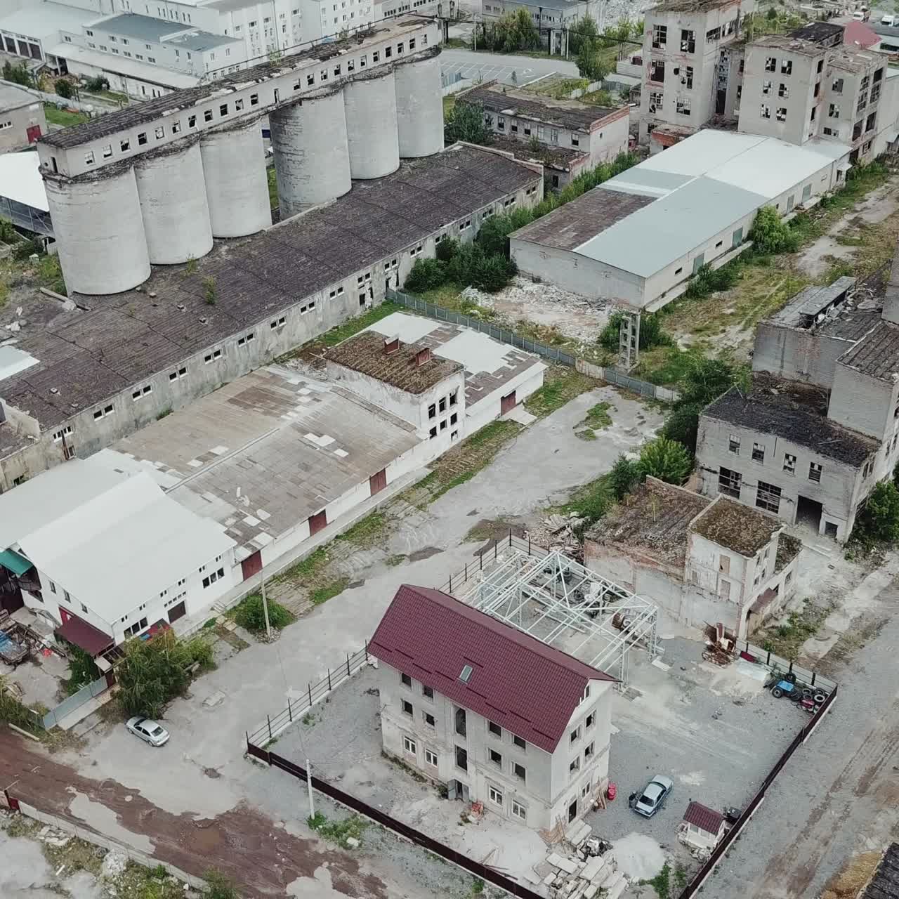 버려진 산업 공장 건물 위를 날아다니며 매우 폐허가 된 상태입니다.