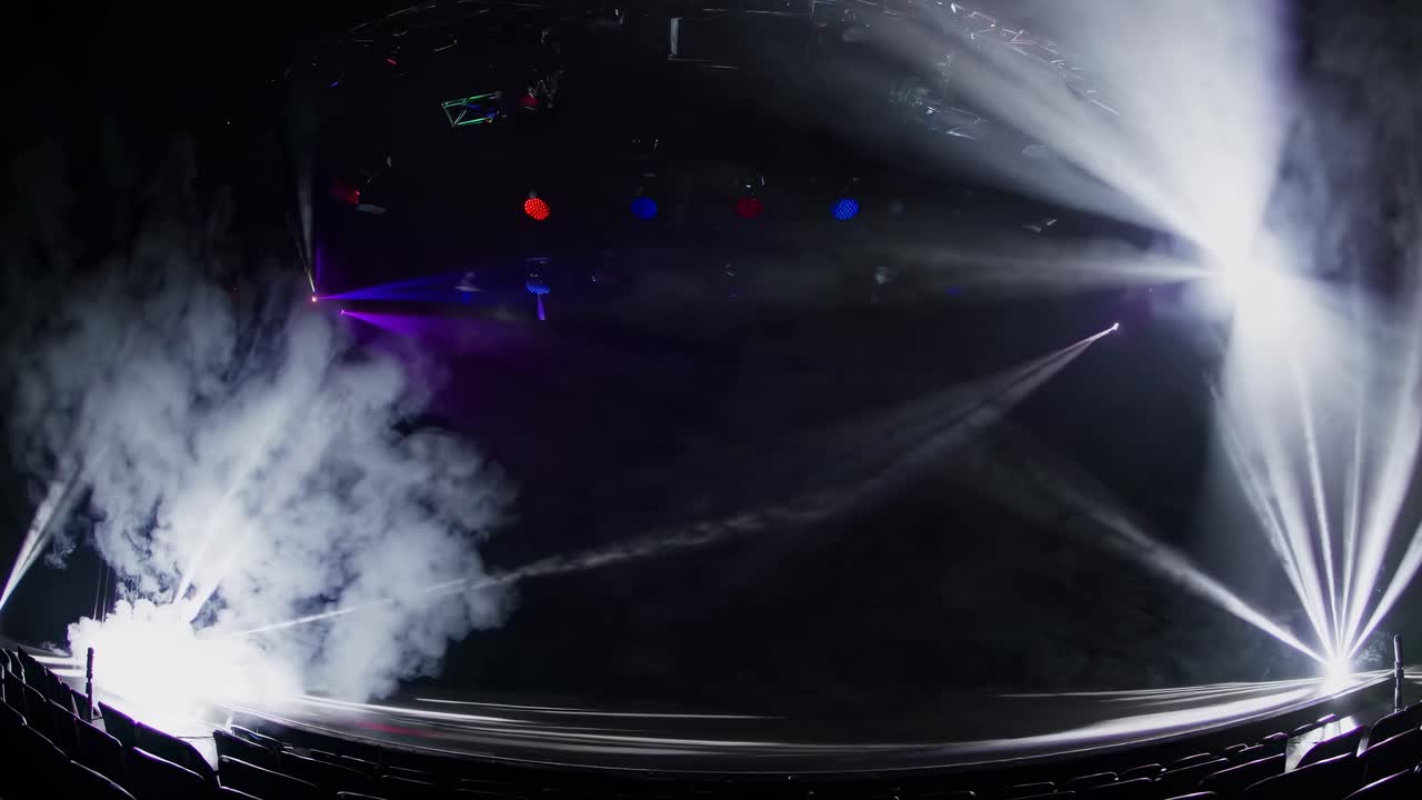Wide-angle shot of a stage with vibrant purple lighting and fog, creating a dramatic atmosphere