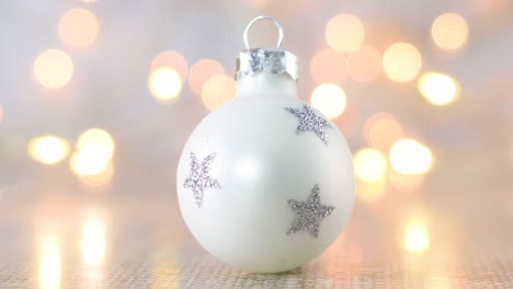 pequeño ornamento de navidad blanco con estrellas brillantes de plata y luces parpadeantes detrás