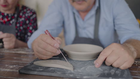 Three-elderly-people-work-on-a-potter's-wheel-in-slow-motion