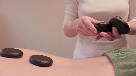 rocas volcánicas en la parte posterior del hombre, tratamiento de masaje con piedras de lava en el centro de spa wellness, primer plano