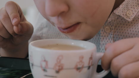 boy blowing on hot tea and cooling it