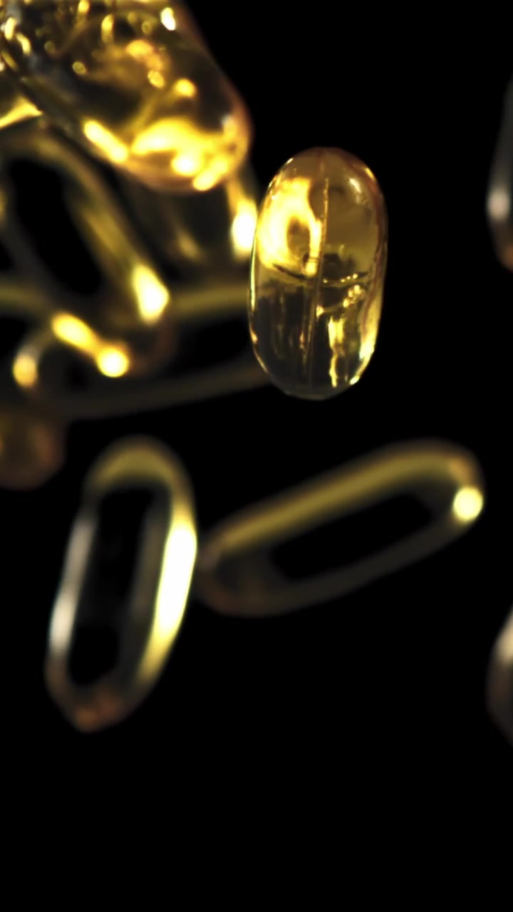 Capsule softgel dorate galleggianti su sfondo nero