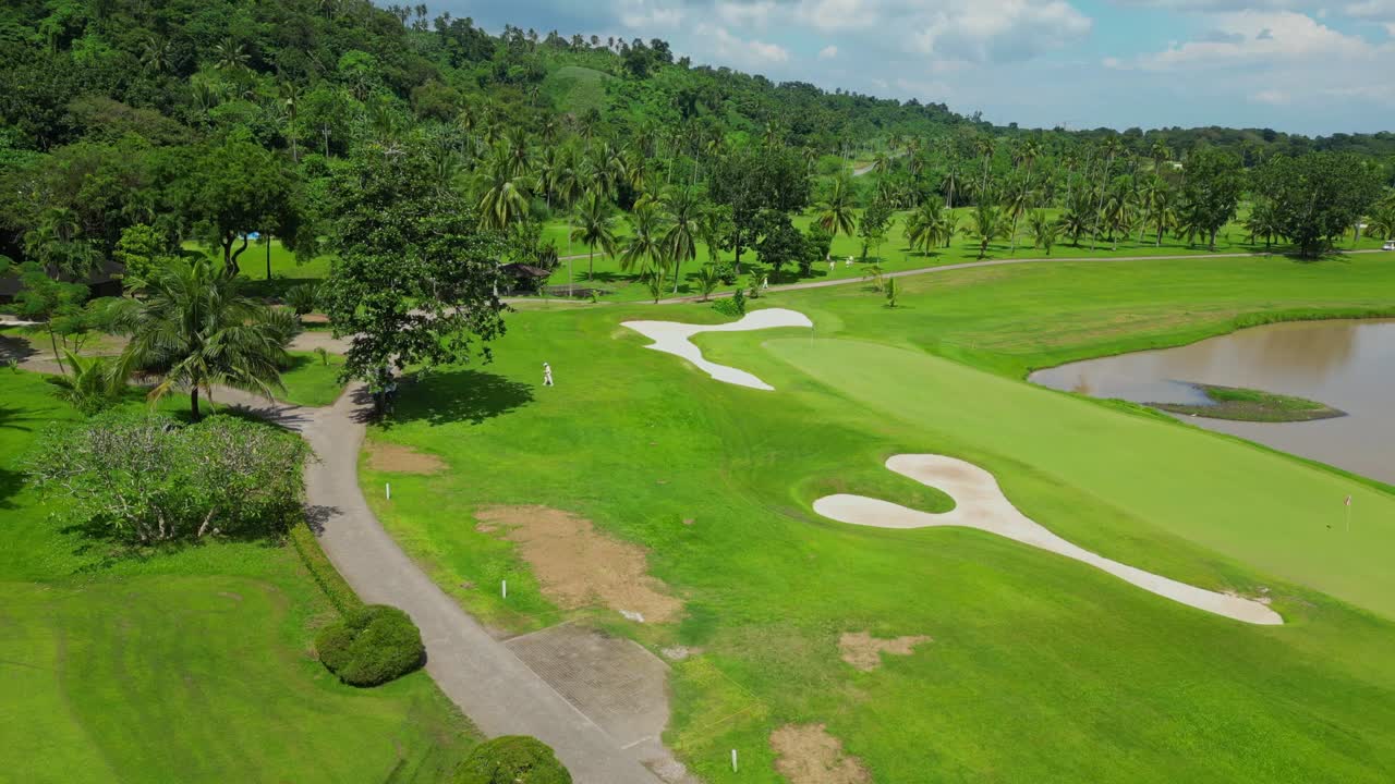 An elevated aerial passing over tropical trees, revealing fairways, water features, and the clubhouse of Canlubang Golf and Country Club in Calamba Laguna, Philippines