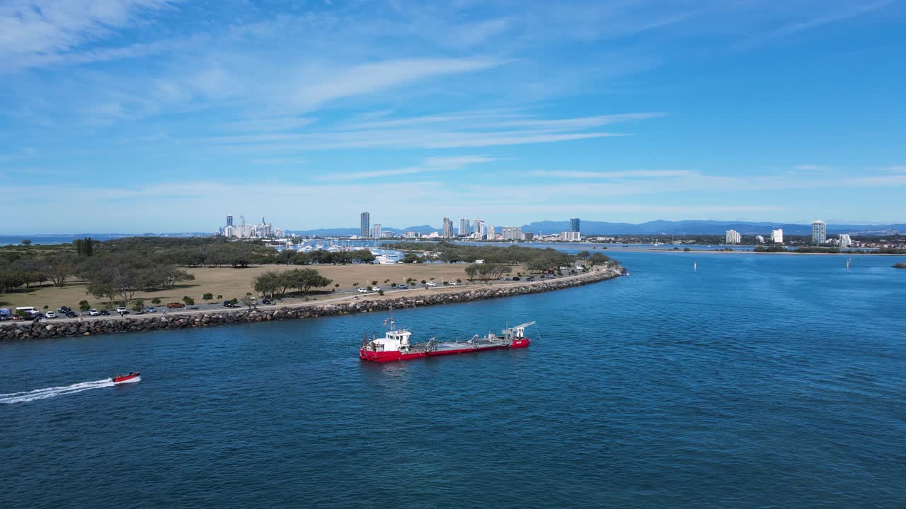 멀리 도시 스카이라인을 배경으로 도시 항로에 위치한 대형 해안 유지 보수 선박을 보여줍니다.
