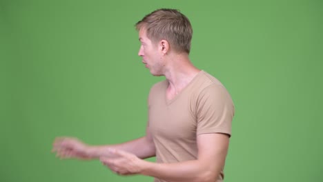 young handsome scandinavian man presenting something against green background