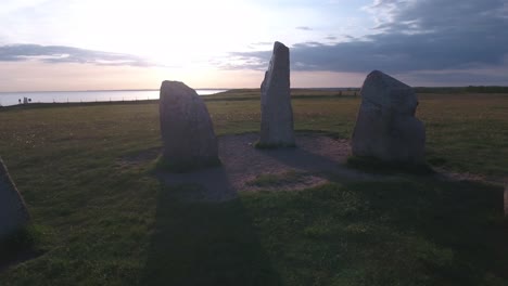 ancient stone ales stenar in the summer evening in south sweden kåseberga österlen, reverse smooth low drone shot