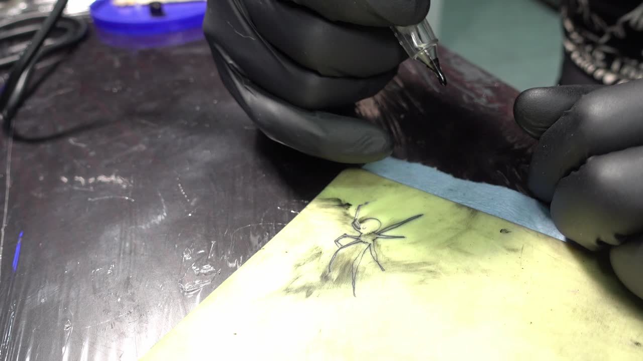 un artista del tatuaje que detalla el tatuaje de una araña negra