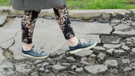 Cracked-asphalt-of-pedestrian-walkway-while-casual-person-walking-on