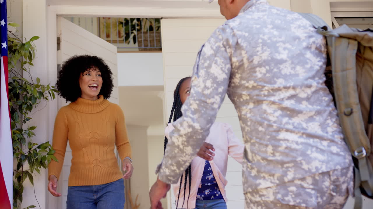 Soldado afro-americano feliz abraçando a família em casa, em câmera lenta
