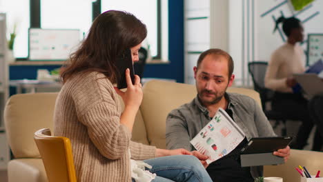 man asking woman manager about graphics while she is talking on smartphone