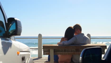 rear view of couple sitting on bench near railings 4k