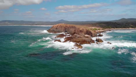 aerial view away from the look at me now headland bay, at the emerald beach, in australia - pull back, drone shot