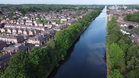 vista aérea volando sobre la rica urbanización de cheshire junto al canal de barcos de manchester disparando hacia adelante