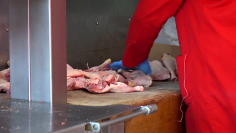 butcher cutting the raw beef meat to pieces slices using big knife in the market of paris, france