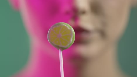mujer lamendo helado con seducción, boca en primer plano sobre fondo verde