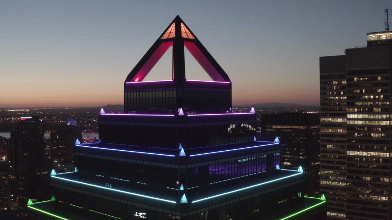Livelli LED colorati e corona a piramide su Place Ville Marie brillano al tramonto mentre la telecamera scorre sullo skyline circostante