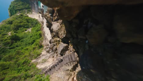 cámara lenta vertical fpv disparó sobre las rocas y la playa de arena tropical en bali en un día soleado