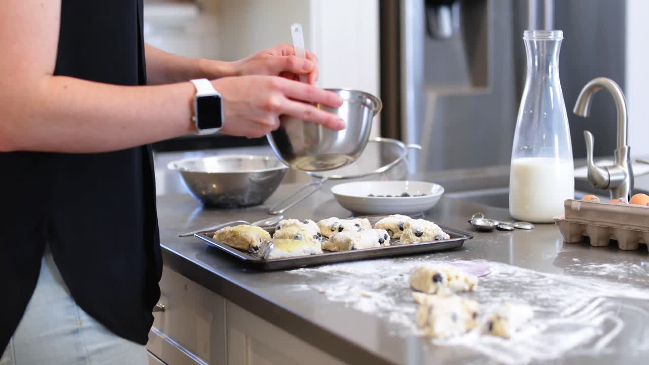 mujer cepillando aceite en la masa de galletas en la cocina4k
