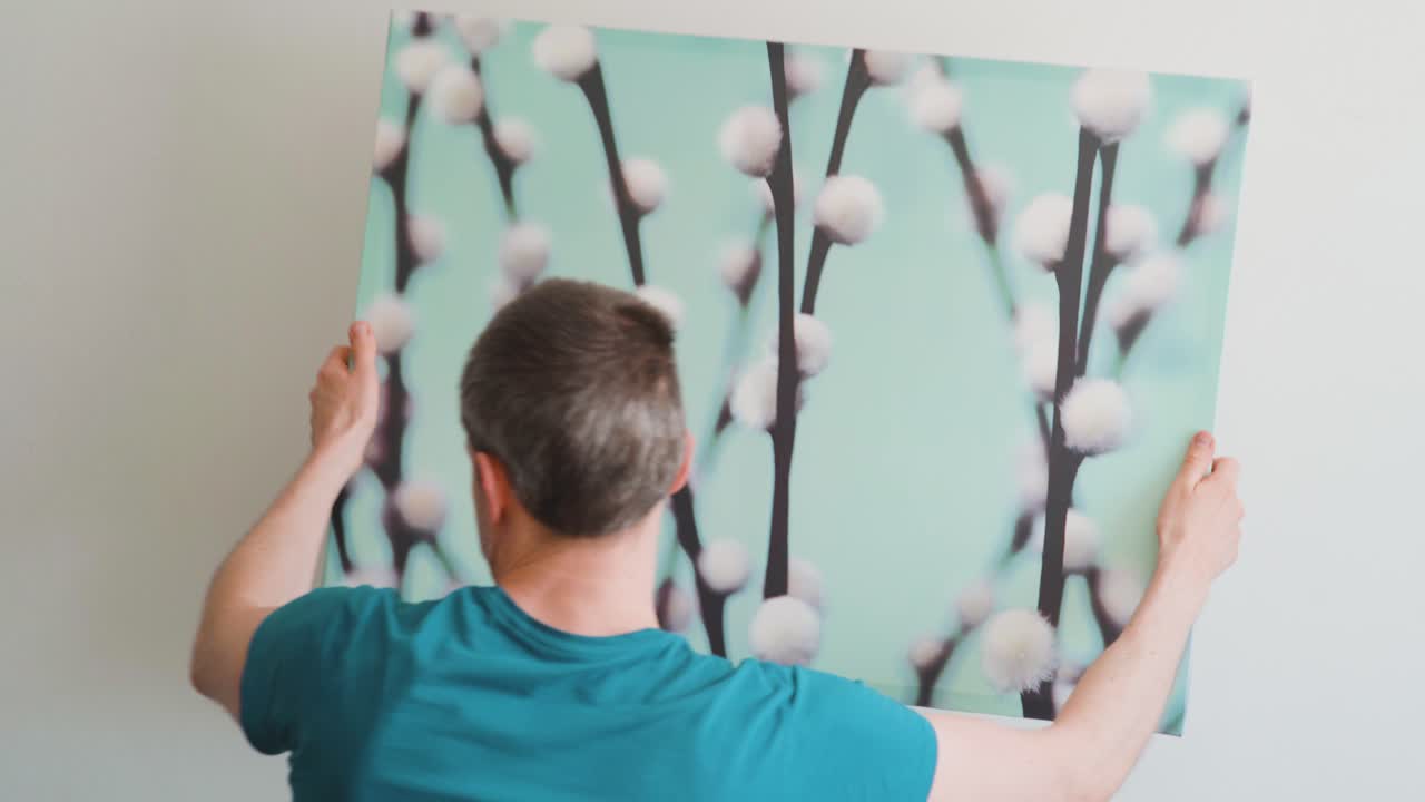 벽에 걸린 사진을 떼어내는 남자