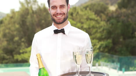 Camarero-Sonriente-Sosteniendo-Una-Botella-De-Champán-Y-Una-Flauta