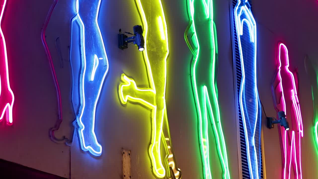 Bright neon outlines in pink, yellow, blue, and green create a dynamic visual on a dark background.