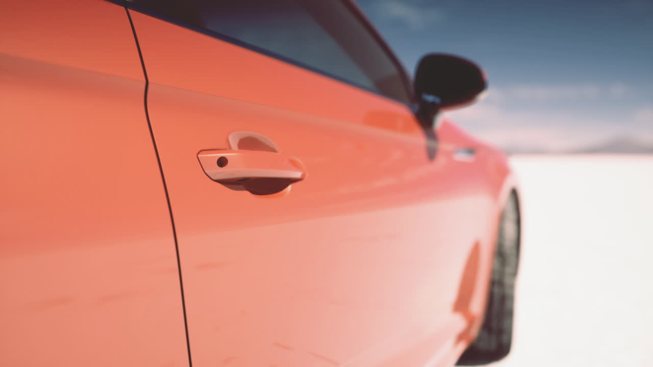 Vibrant orange car parked on a salt flat under a clear blue sky