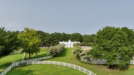 experience the timeless allure of the countryside with this breathtaking aerial view of a pristine white barn nestled amidst the sprawling grounds of an exclusive equestrian club