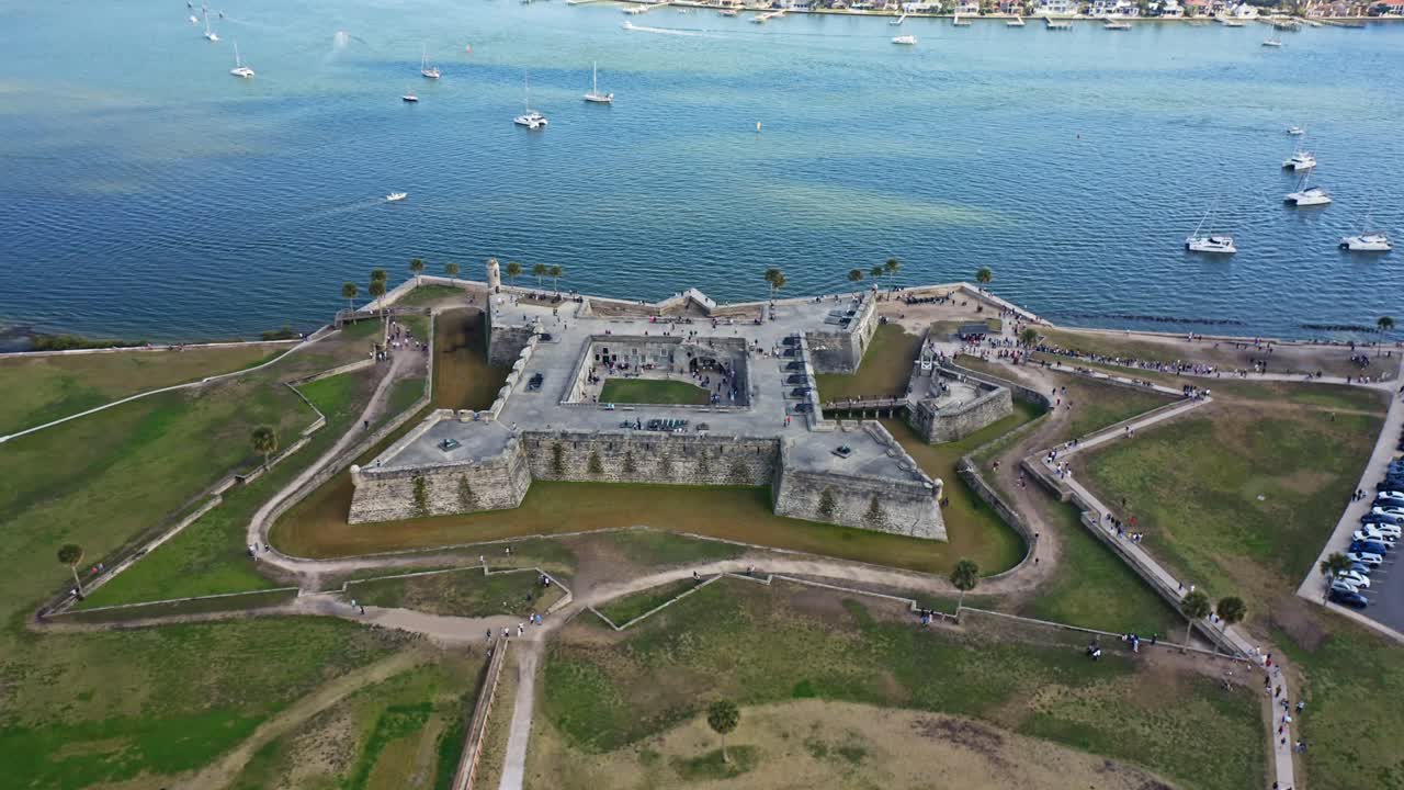 O Castillo de San Marcos em forma de estrela destaca-se proeminentemente à beira-mar, com barcos pontilhando a água. Ideal para documentários históricos e reportagens de viagem