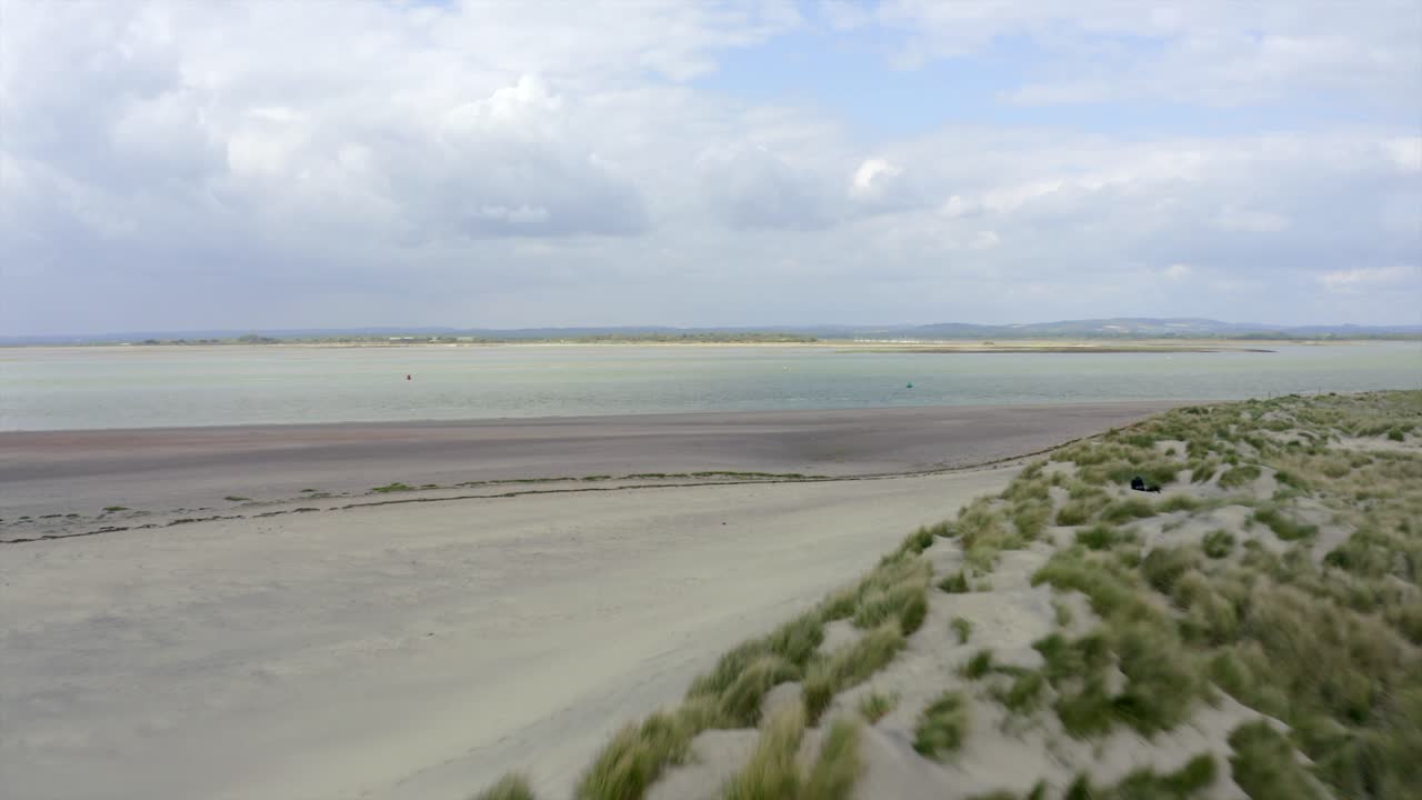 Drone flying over sand dunes at beach coastline.