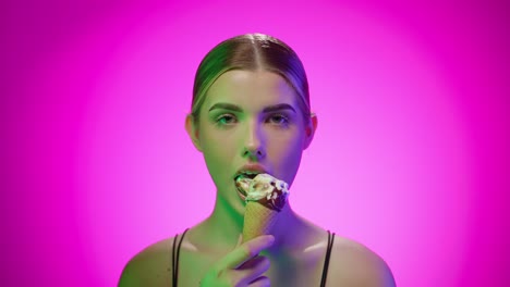 young blonde caucasian woman eats ice cream in a studio with infinite background