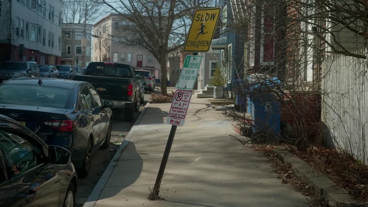 Steady shot of street signboards and parked cars along street in Portland, Maine, USA.
