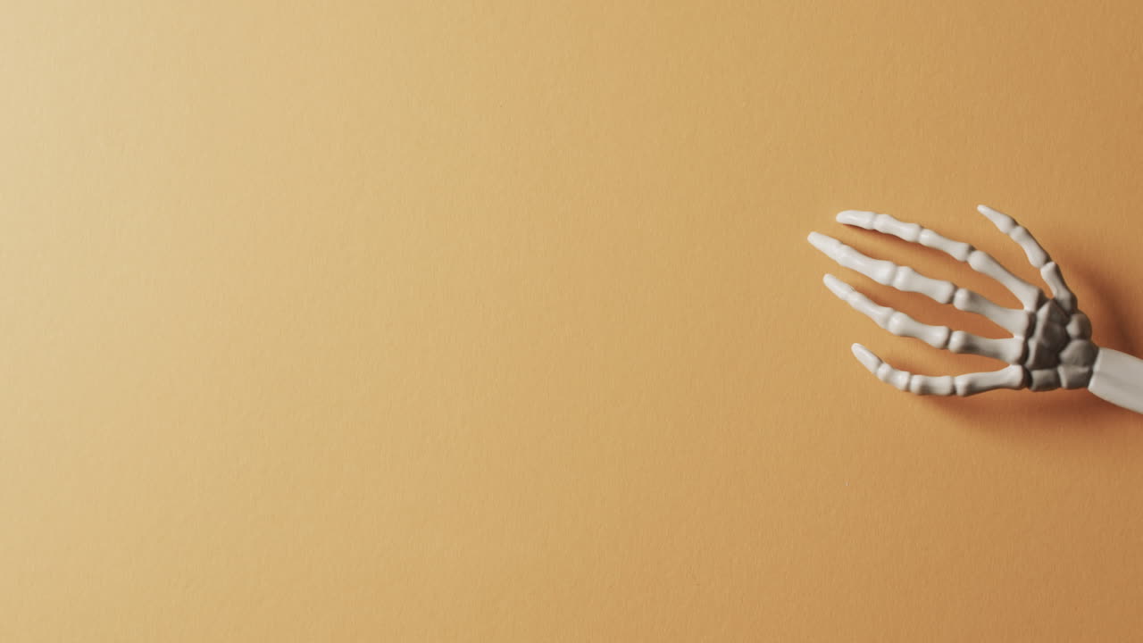 video de las manos del esqueleto de halloween con espacio de copia en fondo naranja