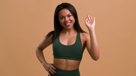 mujer con ropa deportiva mostrando un letrero de "ok"