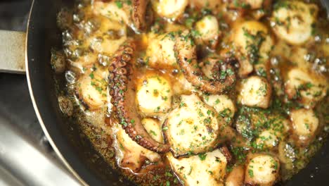 close up shot of cooking fresh octopus in pan with spices at home