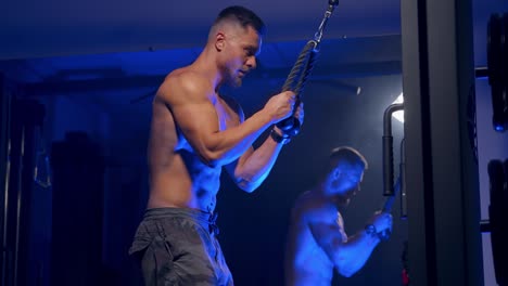 handsome sportsman training muscles. strong athlete finishing his workout in the gym. healthy lifestyle. blue light filter.