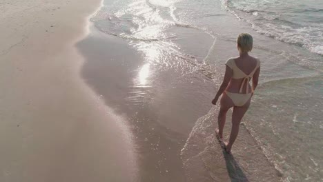 a lady wearing a bikini, walking alone in the water of the beach for a relaxation time in the sunlight