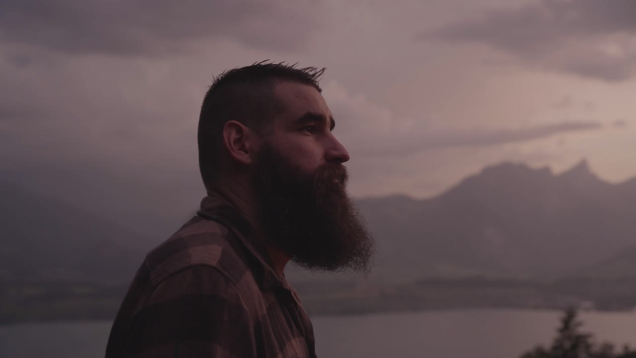 A man gazes toward the mountains at sunset, surrounded by calm nature and soft light. Concept of reflection, solitude, mindfulness, and connection with the natural world